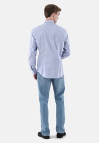 Gestreiftes, hellblau-weißes Hemd zum Aufknöpfen, kombiniert mit hellblauen Jeans. Weicher Baumwollstoff, reguläre Passform, lange Ärmel mit Manschetten.