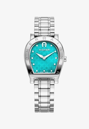 Reloj de pulsera de metal plateado con una caja angular, esfera texturizada color turquesa y marcadores en forma de punto. Logo "AIGNER" destacado en el bisel.