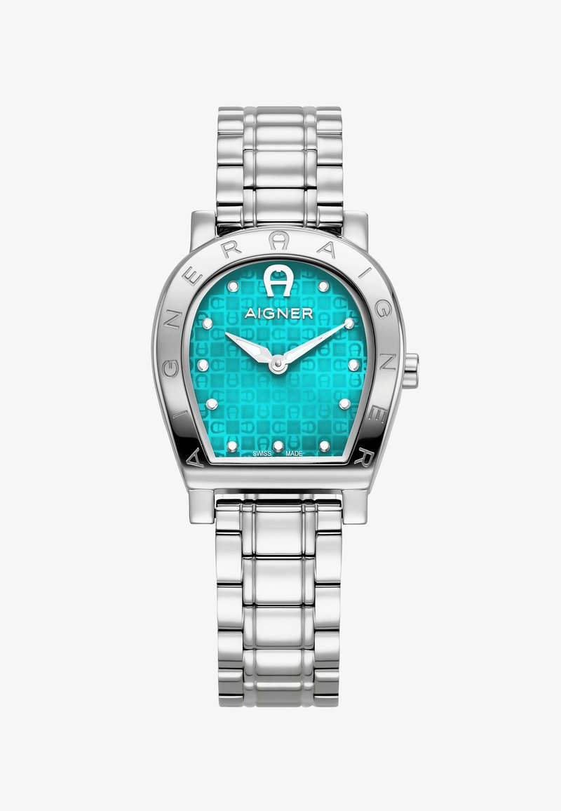 Montre-bracelet en métal argenté avec un boîtier angulaire, un cadran texturé turquoise et des marqueurs en forme de point. Logo "AIGNER" affiché de manière proéminente sur la lunette.