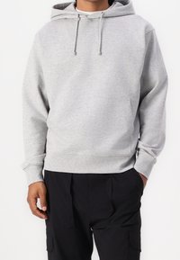 Ljusgrå hoodie i mjukt material, med en framficka, justerbar dragsko i huvan och ribbade ärmslut och nederkant.