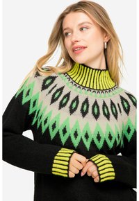 Strickpullover in Schwarz mit einem lebhaften geometrischen Muster in Grün und Grau, ausgestattet mit einem hohen gerippten Kragen und gestreiften Bündchen in strahlendem Gelb.