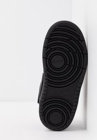 Semelle en caoutchouc noir avec des motifs de semelle circulaires et linéaires, présentant des détails moulés "NIKE" et "ALL DAY PLAY". Matériau non marquant.