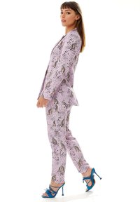 Lilac patterned suit with spotted textures, featuring animal prints. Complemented by blue strappy high heels. Tailored fit with sharp lines.