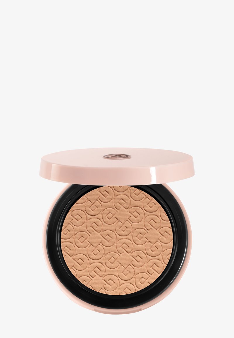 Poudre compacte avec une surface embossée beige clair, présentée dans un boîtier rond rose pâle avec un couvercle partiellement ouvert.
