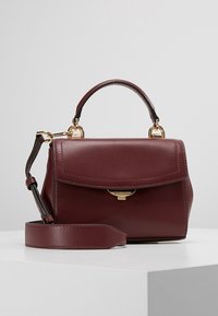 Burgundy læder håndtaske med en struktureret form, top håndtag, aftagelig skulderrem og hardware i guldfarve. Har en klaplukning.