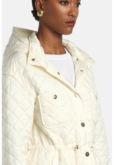 Kreminės spalvos siūtas švarkelis su kapišonu, su spaustukų sagomis, dviem krūtinės kišenėmis ir reguliuojama juosmens raišteliu, suteikiančiu prigludusį siluetą.