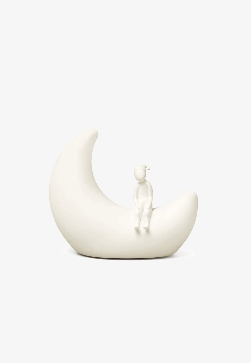 Λευκό γλυπτό σε σχήμα ημισελήνου με μια μικρή καθιστή φιγούρα που φοράει νυχτικό καπέλο στην εσωτερική καμπύλη του φεγγαριού, πάνω σε απλό λευκό φόντο.