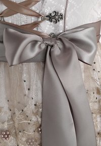 Robe beige clair avec broderies florales, ornée de perles et de perles fines. Dotée d'un nœud en satin et d'un détail corset en ruban taupe.