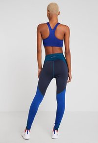 Top sportivo blu con un design testurizzato, abbinato a leggings aderenti con sezioni a blocchi di colore in blu navy e blu brillante.