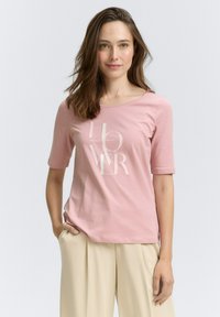 Helles rosa Baumwoll-T-Shirt mit kurzen Ärmeln und rundem Ausschnitt, versehen mit weißen Textgrafiken in moderner Schriftart. Glatte Textur.
