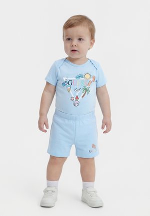 Tout-petit portant une tenue d'été bleu clair composée d'un short et d'un t-shirt illustrés avec un soleil, un palmier, une glace et des tongs.