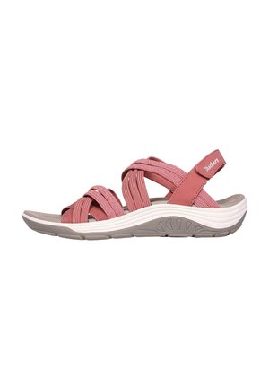 Sandalias con tiras de tela rojas y rosas, con una suela flexible blanca y gris, que presentan tiras trenzadas y una correa ajustable en el tobillo.