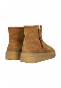 Botas de tobillo de ante marrón con cremallera lateral, superficie texturizada y suela de goma gruesa de color claro. Acabado suave, diseño minimalista.