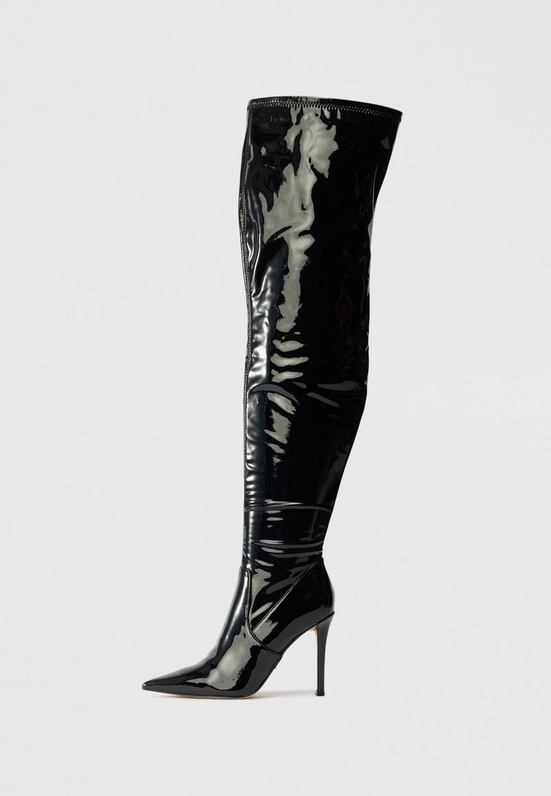 Bottines noires à talons hauts, au-dessus du genou, en cuir verni brillant, dotées d'un bout pointu et d'une texture lisse et élégante.