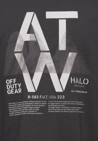 Mörkgrå t-shirt med ögonfångande vit text och grafik. Designen inkluderar "ATW," "OFF DUTY GEAR," och olika militära referenser.
