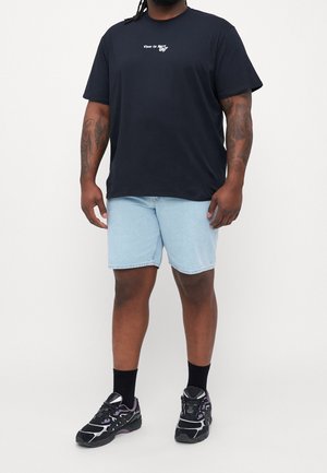 Musta lyhythihainen t-paita valkoisella tekstillä, vaaleansiniset farkkushortsit, mustat lenkkarit violeteilla yksityiskohdilla ja mustat sukat.