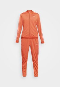 Survêtement Adidas orange avec des bandes blanches sur les manches et les pantalons, veste zippée et poignets et taille élastiques.