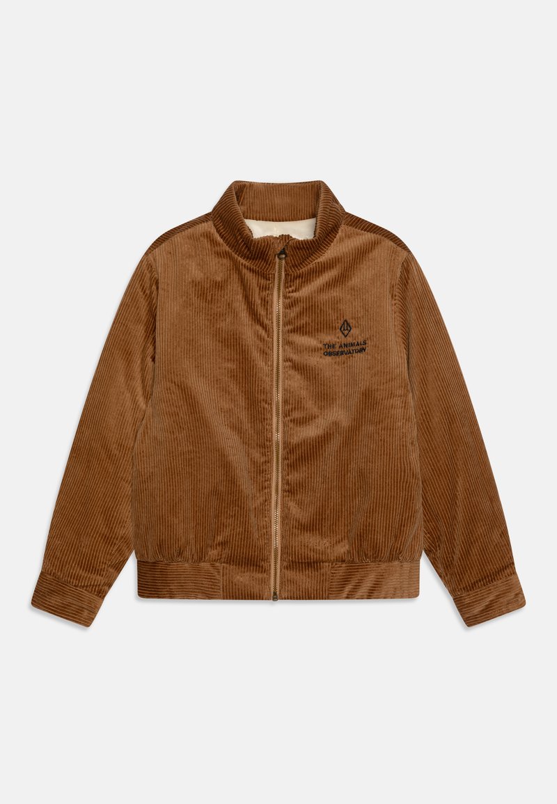 Ruda aksominė striukė su aukšta apykakle, priekyje užtrauktuku ir raštuotais rankogaliais. Kairiajame krūtinės srityje yra išsiuvinėtas logotipas.