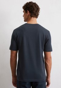 Marineblauw katoenen t-shirt met korte mouwen, ronde hals en subtiele detail van het label aan de achterkant. Gladde textuur en ontspannen pasvorm.