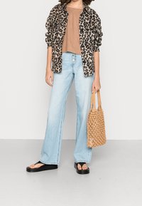 Chemise imprimé léopard, haut marron, jean large bleu clair, sandales compensées noires et sac tissé beige. Texture lisse et coupe décontractée.