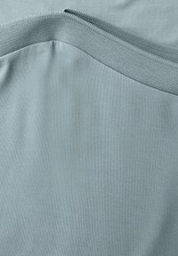 Tessuto blu chiaro con una superficie liscia, caratterizzato da una sezione a maglia ribbed lungo il bordo superiore e una superficie piatta sottostante.