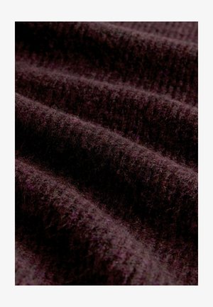 Tamno ljubičasta tkanina s teksturiranim, ribastim uzorkom i mekom, pahuljastom površinom, koja prikazuje blage nabore i valove u materijalu.