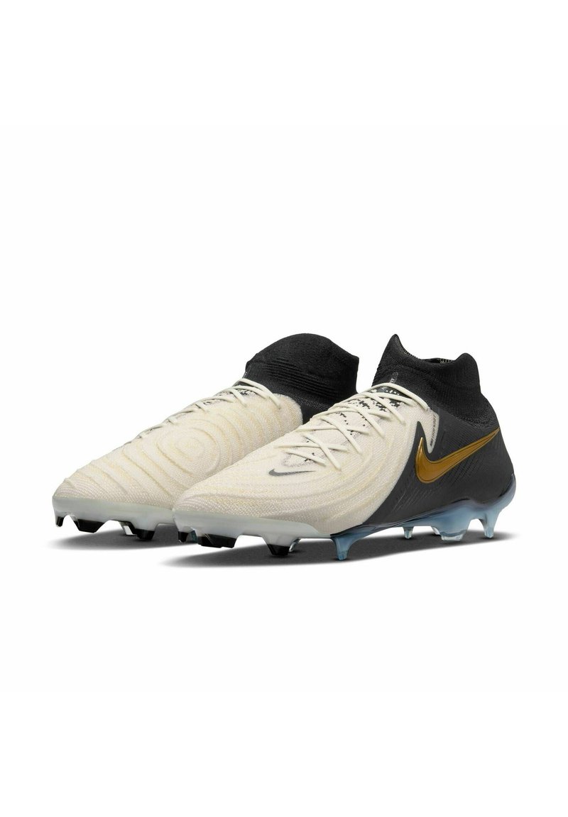 Nike-Fußballschuhe mit einem weißen und schwarzen Obermaterial mit strukturierten Mustern, einem hohen Knöcheldesign und einem goldenen Swoosh-Akzent. Durchsichtige Sohle.