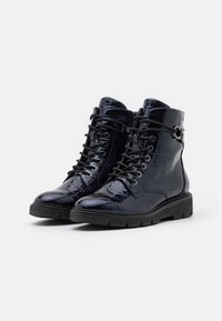 Bottines en cuir verni noir avec une texture crocodile, présentant un bout rond, un design à lacets et une semelle en caoutchouc épaisse.