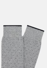 Calcetines grises con un tejido texturizado, que presentan pequeños puntos negros y un puño acanalado de color azul marino oscuro. Material suave con un ajuste flexible.