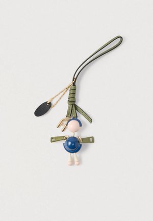 Atslēgu piekariņš ar krāsainu tēlu — rozā galva, zils ķermenis un zaļas siksnas, papildināts ar zelta detaļām un baltajiem akcentiem.