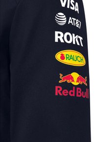 Granatowy sweatshirt z logo: Visa, AT&T, Rokt oraz żółtym Rauch, a na rękawie czerwono-żółte logo Red Bull.