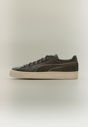 Czarny niski sneaker z białą podeszwą i bocznym paskiem, cholewką z teksturowanej skóry oraz czarnymi sznurowadłami, pokazany z boku na beżowym tle.
