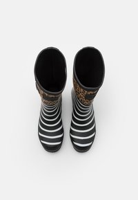 Bottes de pluie en caoutchouc noires avec des rayures horizontales blanches et un accent imprimé léopard marron en haut ; texture lisse, forme arrondie.