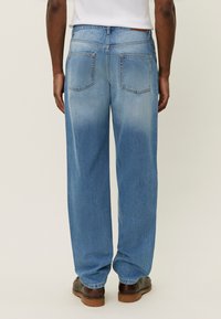 Lyseblå denimjeans med en avslappet passform, som har to baklommer og en gradvis falming fra mørkere til lysere nær kanten.