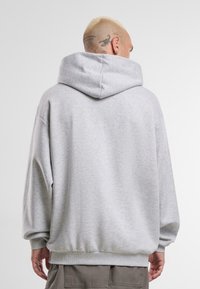 Gray hoodie with a spacious hood, ribbed cuffs, and a relaxed fit. The fabric has a smooth texture and subtle heather pattern.