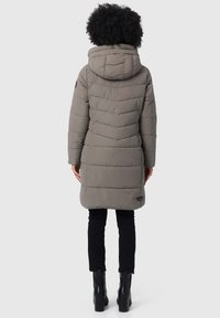 Lange, grijze pufferjas met een capuchon, met horizontale en chevron gestikte patronen, en een merkbadge nabij de zoom. Draag met zwarte broek en laarzen.