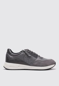 Sneaker grigio con una combinazione di materiali texturizzati e lisci, chiusura con lacci e cerniera, suola bianca e dettagli neri.