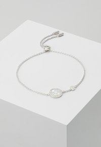 Silberarmband mit einem runden, gemusterten Anhänger mit kreisförmigen Einlagen. Glatte Kette mit einem Schiebverschluss für eine verstellbare Passform.