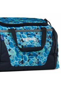 Bolsa de deporte con patrón abstracto azul; la tela tiene una textura suave, con un cierre de cremallera y asas negras. Logo mostrado en blanco.