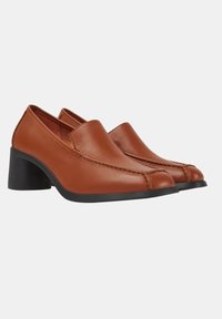 Chaussures à talon en cuir brun avec un bout arrondi, des coutures décoratives sur le devant et un talon noir épais. Texture lisse dans l'ensemble.