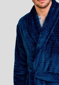 Bata de baño azul marino hecha de un tejido de felpa con un patrón de cuadros texturizado, que cuenta con un cuello tipo chal y un cinturón atado.