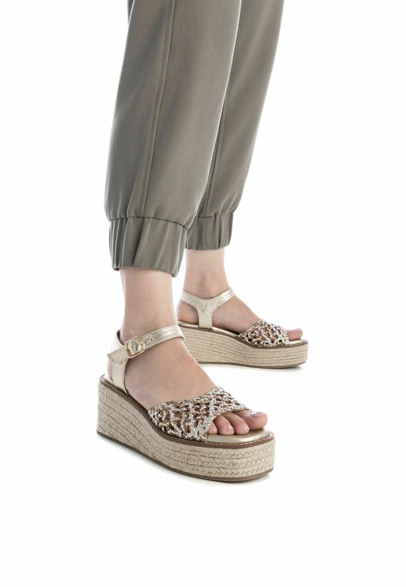 Sandali con zeppa e piattaforma in paglia intrecciata, fascia dorata e dettagli in accentuazione, design open toe, impreziositi con fili metallici.