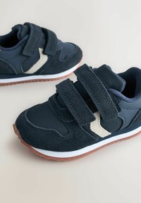 Pair of navy blue children's sneakers with white detail, brown soles, and double Velcro straps on a light background.