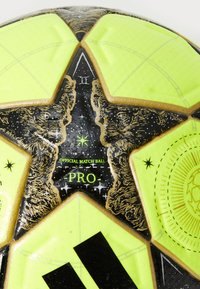 Pallone ufficiale con pannelli verde lime vibrante, accenti neri con motivi a stella, dettagli dorati e superficie testurizzata.