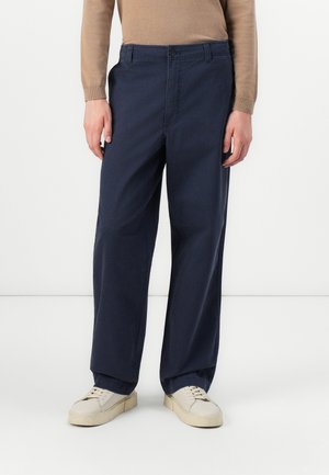 Navyblå chinos med rak passform, featuring en knappstängning fram, sidofickor och mjukt bomullstyg. Matchas med krämfärgade sneakers.