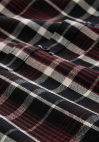 Tkanina w kratę w kolorach granatowym, czerwonym i białym, o miękkiej teksturze i z detalem guzikowym. Wzór składa się z naprzemiennie ułożonych krat i pasków.