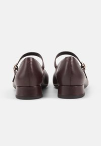 Burgundy bőr cipők, lekerekített orral és alacsony sarkúval, aranyszínű csattal ellátott bokaövével. Simító felület, minimalista dizájn.