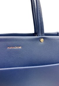 Borsa a tracolla in pelle blu con una texture, dotata di due manici, con un logo dorato e il nome "MARIACELINE" sulla parte anteriore.
