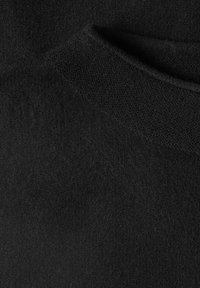 Gros plan sur un tissu texturé noir montrant un tricot fin et des plis doux en surface.
