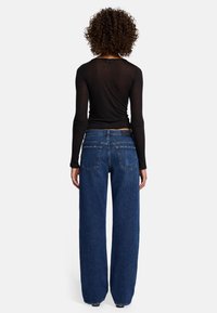Jeans a vita alta e gamba larga in denim blu scuro con una texture liscia. Presentano due tasche posteriori e un'etichetta del marchio discreta sopra la vita.